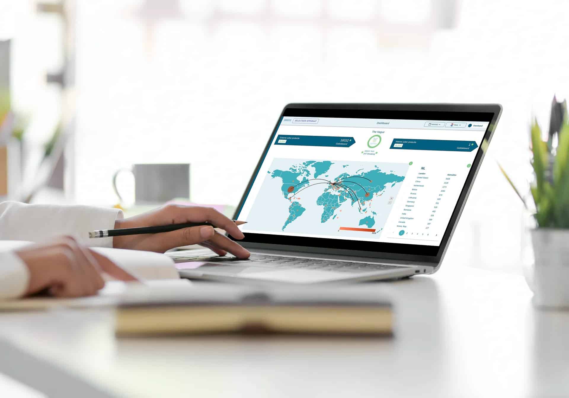 A photograph of hands working on a laptop displaying a world map dashboard for logistics or business tracking.