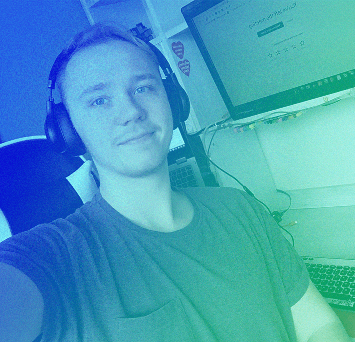 Young person wearing headphones working at a computer desk with dual monitors in a home office setup