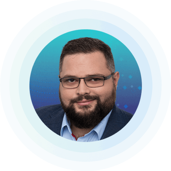 man with glasses and a beard, wearing a suit jacket and shirt, is centered on a blue gradient circular background.