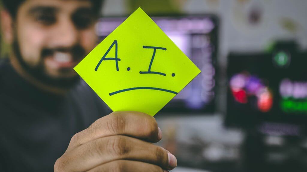 A man holding a piece of paper with "A.I." written on it
