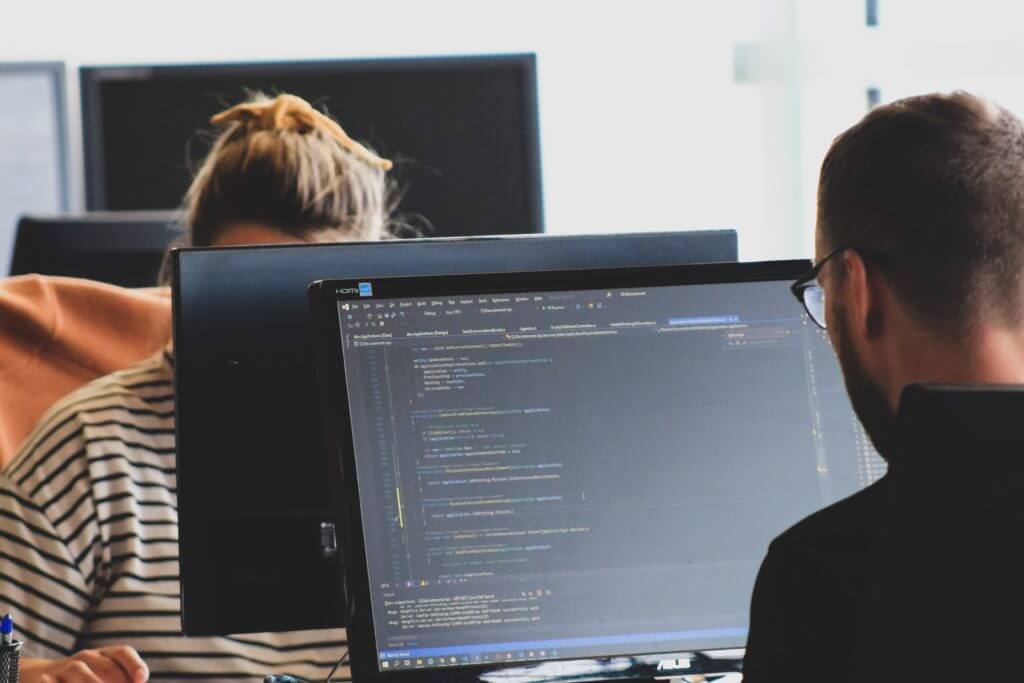 Programmers reviewing application code written with TypeScript in Node.js during a team project.