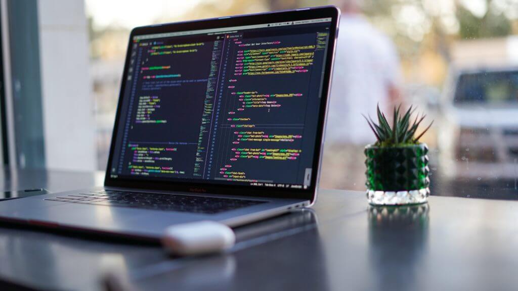 Laptop displaying code in a text editor, representing the difference between Node.js and React in web application development.