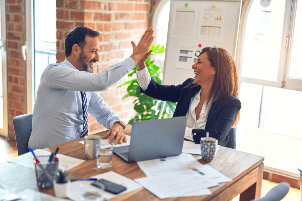 a picture of co-workers giving each other a high five in reference to digital twin helping introduce a more collaborative approach in teams