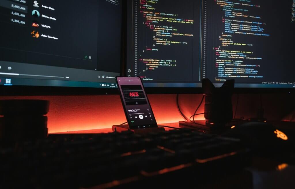Dual monitors displaying code in a dark workspace representing bespoke software development services.