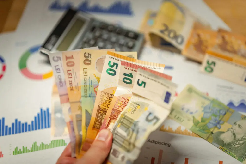 AI Development costs represented by euro and Romanian leu banknotes, a calculator, and financial charts