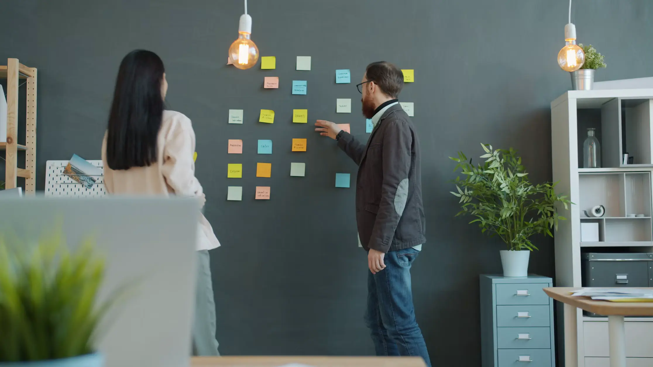Two workshop participants planning product ideas with sticky notes on a wall
